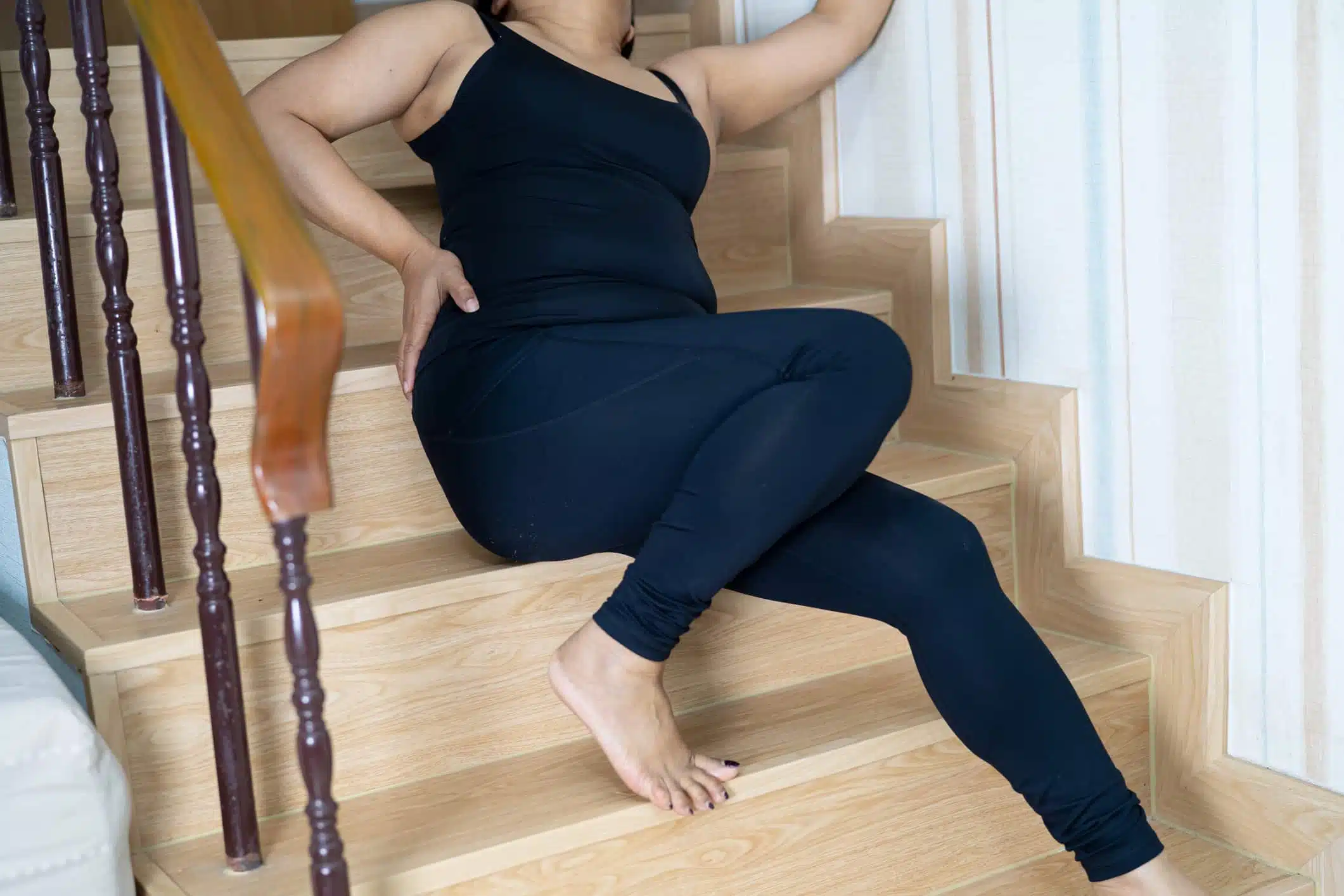 Lady sitting on stairs with injury from slipping and falling on slippery stairs