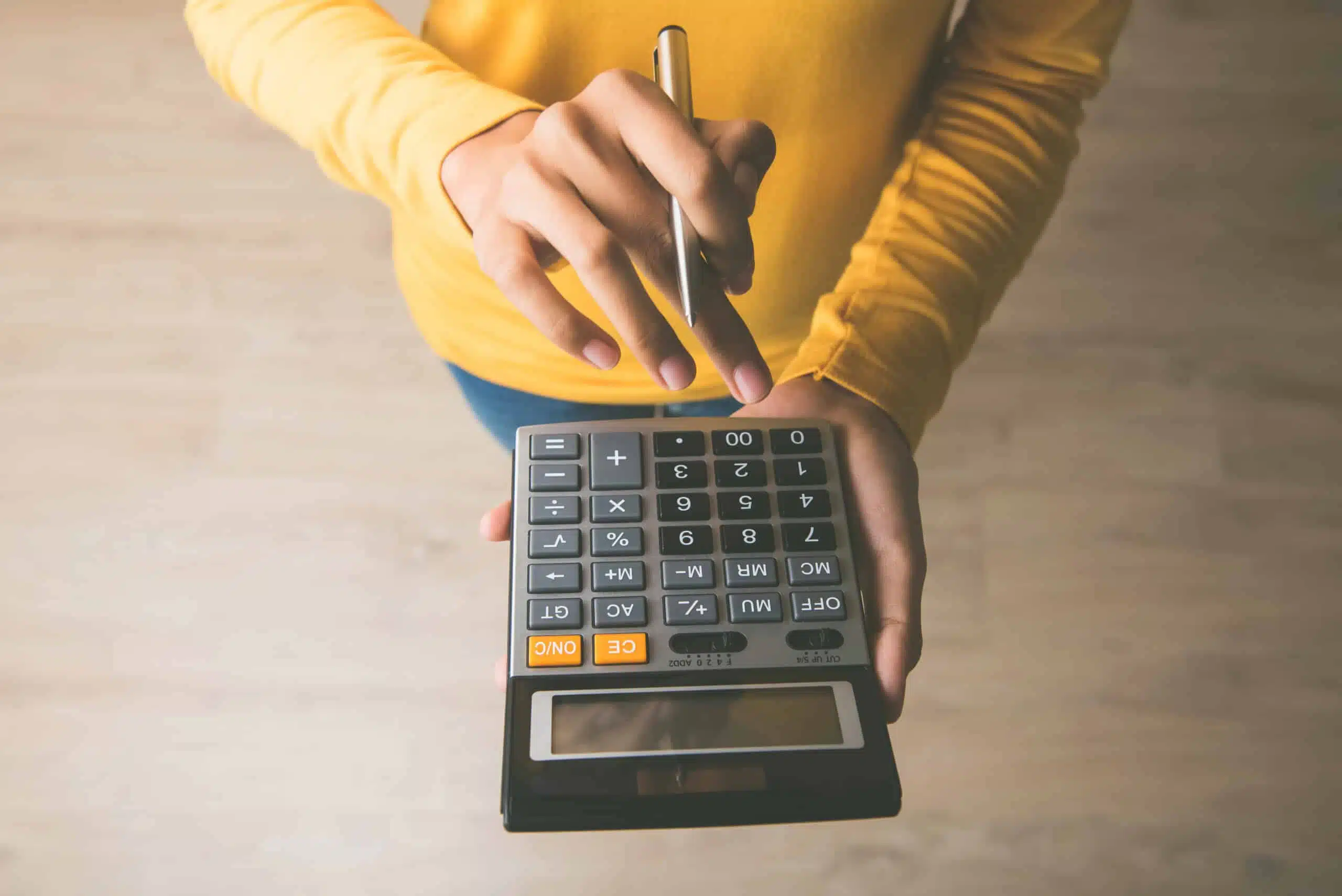 woman standing with calculator working out Non-Slip Flooring prices and how Slip No More can help you