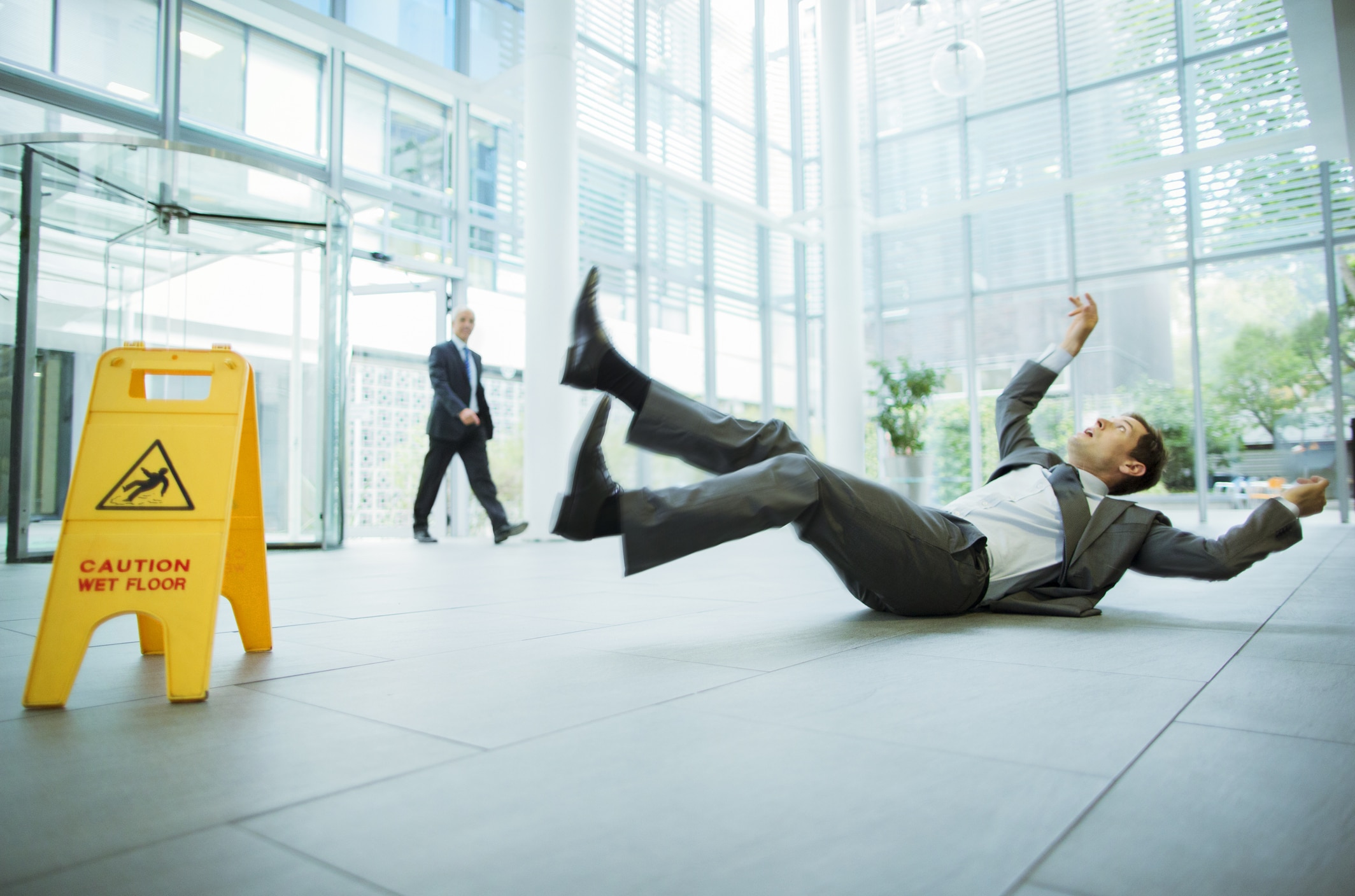 Businessman slipping on floor of office building due to no anti-slip flooring installed