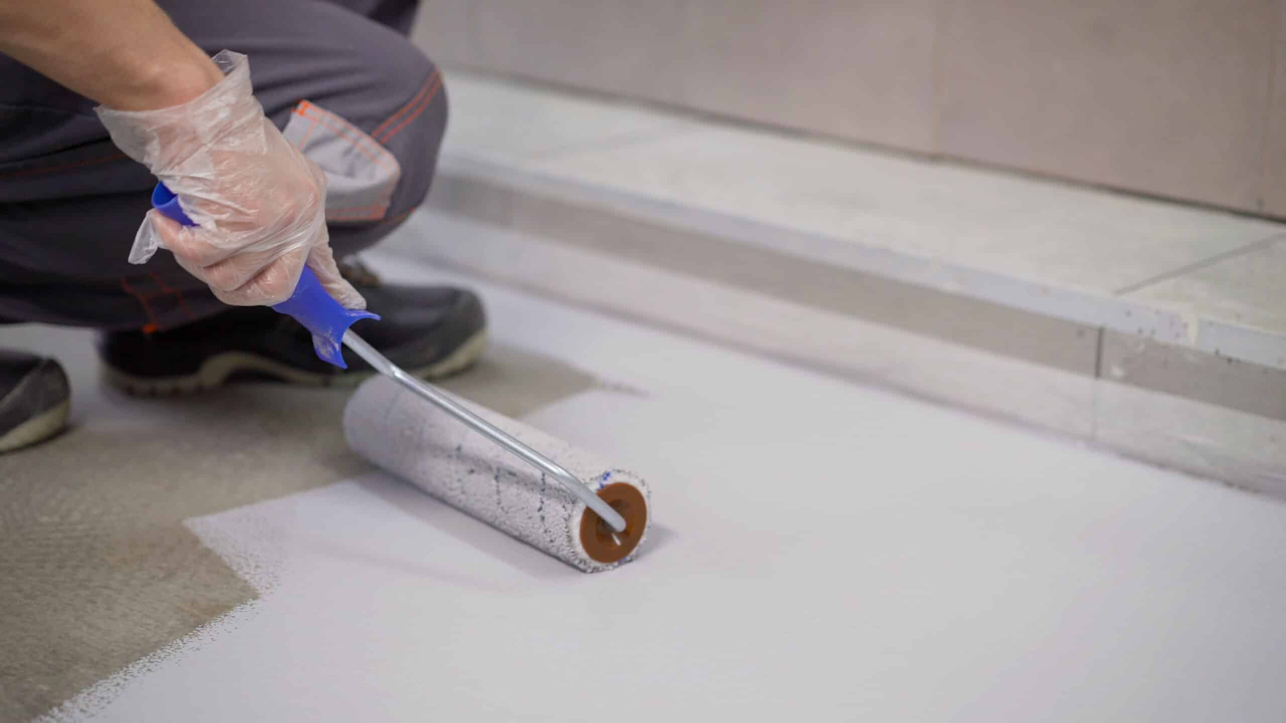 A worker applying Concrete Non-Slip Paint with a roller for the purpose of slip prevention